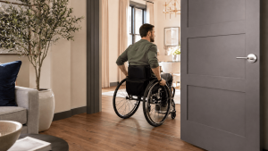 Wheelchair user traveling through a wide interior doorway with sufficient clear opening and a smooth, low-profile threshold.